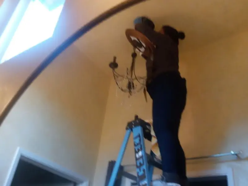 Electrician installing a chandelier in a South Lebanon residence